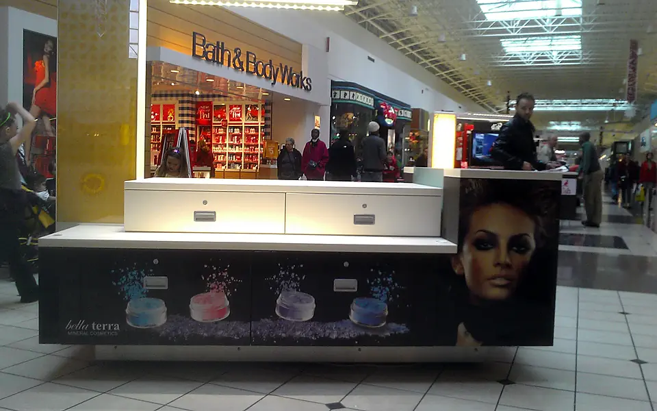 A white BELLATERRA mineral cosmetics kiosk in a shopping mall